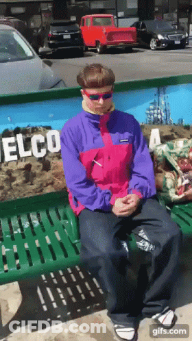 A Man In A Pink And Purple Jacket Is Sitting On A Bench In Front Of A Wall That Says Elco GIF