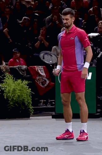 A Man In A Pink And Purple Shirt Holds A Tennis Racquet GIF