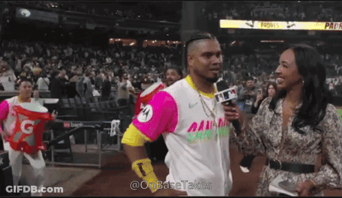 A Man In A Pink And Yellow Jersey Is Being Interviewed By A Female Reporter GIF