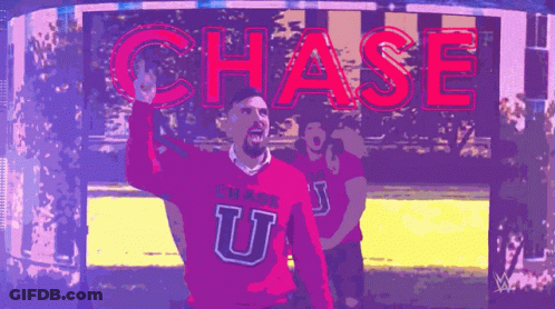 A Man In A Pink Chase U Sweater Stands In Front Of A Chase Sign GIF
