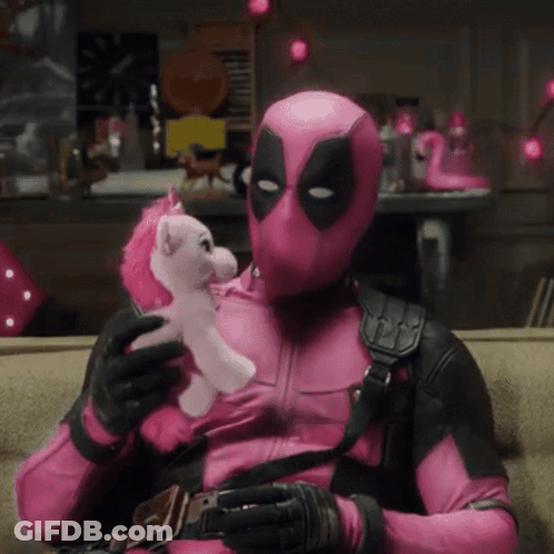 A Man In A Pink Deadpool Costume Is Holding A Pink Unicorn GIF