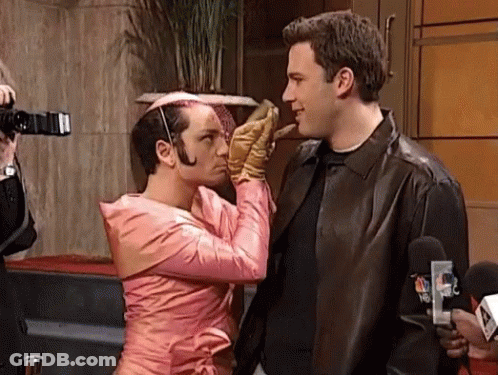 A Man In A Pink Dress Is Kissing Another Man On The Cheek GIF