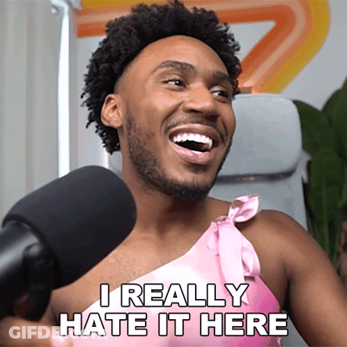 A Man In A Pink Dress Is Laughing And Says I Really Hate It Here GIF
