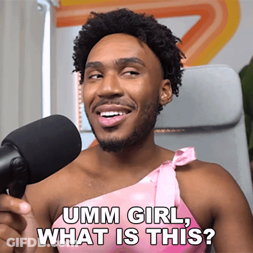 A Man In A Pink Dress Is Talking Into A Microphone And Asking " Umm Girl What Is This " GIF