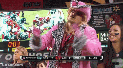 A Man In A Pink Fur Coat Stands In Front Of A Scoreboard That Says Walmart GIF