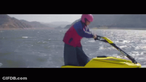 A Man In A Pink Helmet Is Riding A Jet Ski GIF
