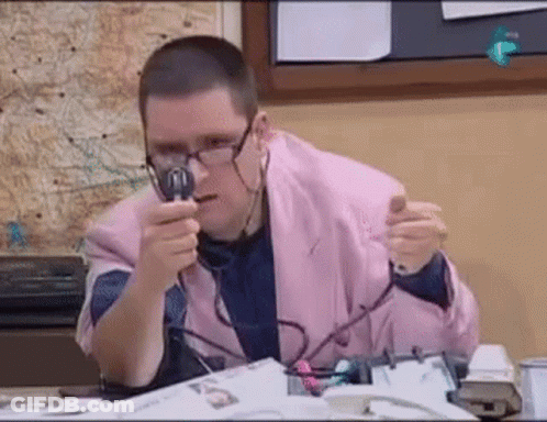 A Man In A Pink Jacket Is Holding A Magnifying Glass In Front Of His Face . GIF