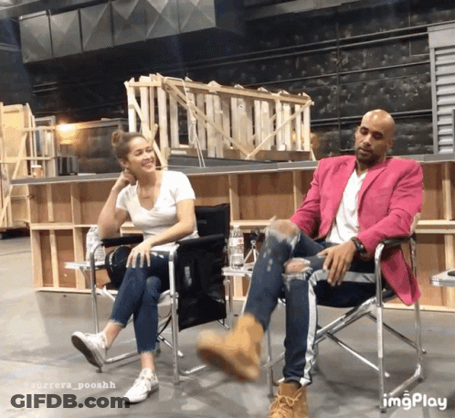 A Man In A Pink Jacket Sits Next To A Woman In A Chair GIF