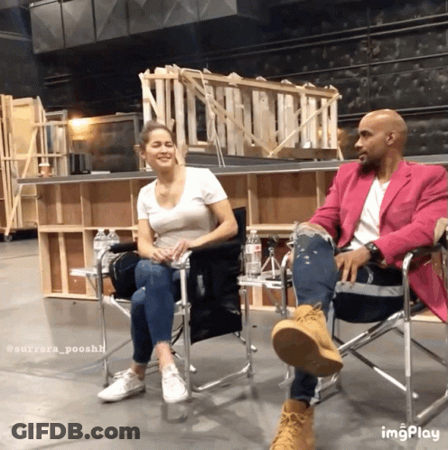 A Man In A Pink Jacket Sits Next To A Woman In Chairs GIF