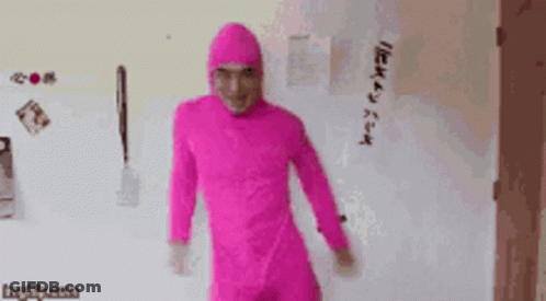 A Man In A Pink Jumpsuit Is Standing In Front Of A Refrigerator . GIF