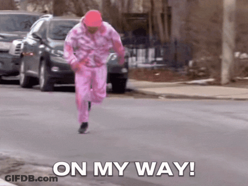 A Man In A Pink Outfit Is Running Down The Street With The Words On My Way GIF