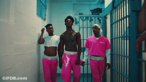 A Man In A Pink Prison Uniform Is Walking With Two Other Men GIF
