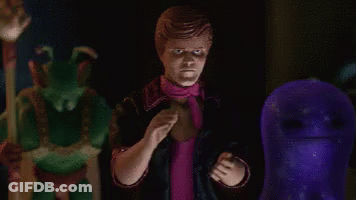 A Man In A Pink Scarf Is Standing In Front Of A Purple Ghost . GIF