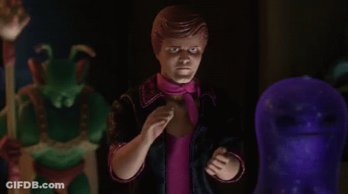 A Man In A Pink Scarf Is Standing Next To A Purple Ghost GIF