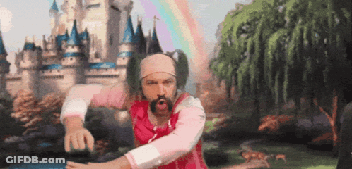 A Man In A Pink Shirt And Headband Is Dancing In Front Of A Castle GIF