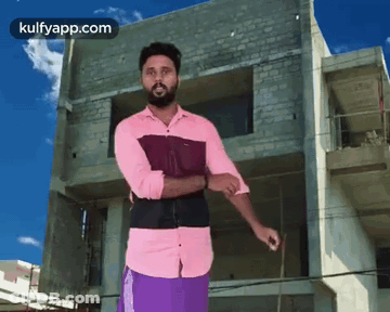 A Man In A Pink Shirt And Purple Shorts Is Standing In Front Of A Building Under Construction GIF