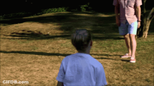 A Man In A Pink Shirt And Shorts Stands Next To A Girl In A White Shirt GIF