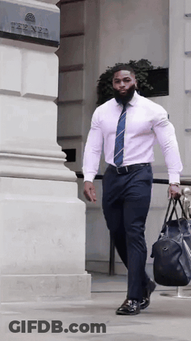 A Man In A Pink Shirt And Tie Is Carrying A Black Bag GIF