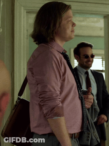 A Man In A Pink Shirt And Tie Is Standing Next To Another Man GIF