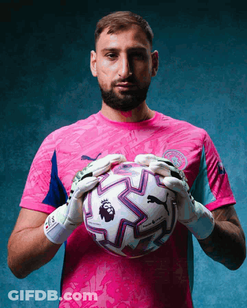 A Man In A Pink Shirt Holds A Soccer Ball With The Word Premier League On It GIF