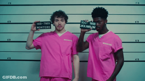 A Man In A Pink Shirt Holds Up A Sign That Says " Montero " GIF