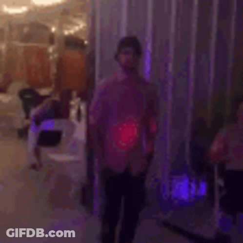 A Man In A Pink Shirt Is Dancing On A Dance Floor In A Room . GIF