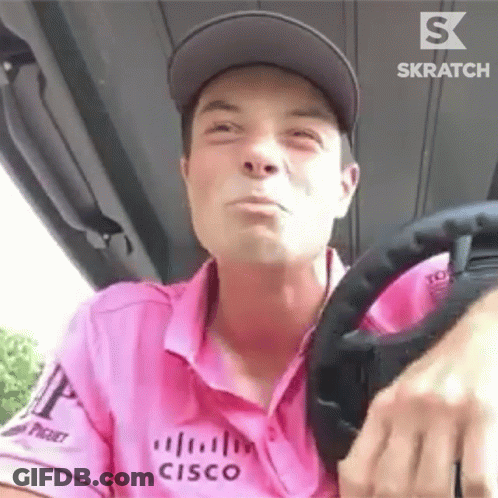 A Man In A Pink Shirt Is Driving A Golf Cart . GIF