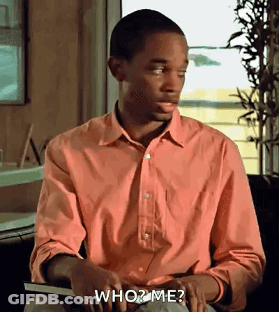 A Man In A Pink Shirt Is Holding A Book And Asking Who Me ? GIF