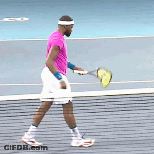 A Man In A Pink Shirt Is Holding A Tennis Racket GIF