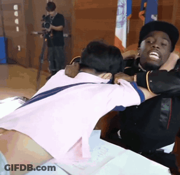 A Man In A Pink Shirt Is Hugging Another Man In A Black Hat GIF