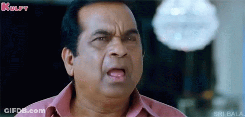 A Man In A Pink Shirt Is Making A Funny Face And Looking At The Camera . GIF