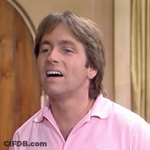 A Man In A Pink Shirt Is Making A Funny Face And Smiling . GIF