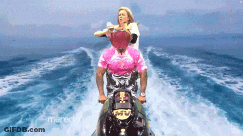 A Man In A Pink Shirt Is Riding A Jet Ski In The Water GIF