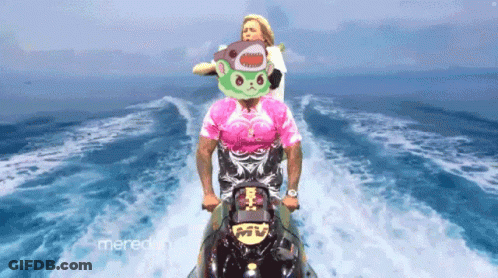 A Man In A Pink Shirt Is Riding A Jet Ski With A Woman In A Shark Mask Behind Him GIF