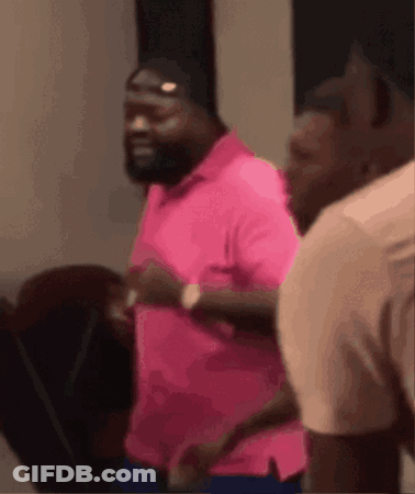 A Man In A Pink Shirt Is Running On A Treadmill With Other Men . GIF