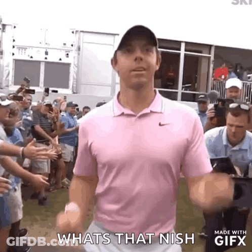 A Man In A Pink Shirt Is Standing In Front Of A Crowd And Says Whats That Nish . GIF