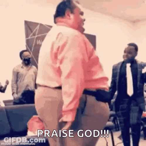 A Man In A Pink Shirt Is Standing In Front Of A Group Of People In A Church And Praising God . GIF