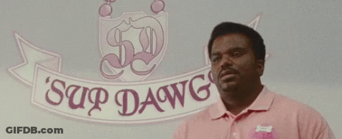 A Man In A Pink Shirt Is Standing In Front Of A Sign That Says Sup Dawg Dawg . GIF