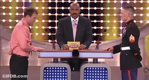 A Man In A Pink Shirt Is Standing Next To A Man In A Military Uniform On A Game Show Called Family Feud GIF