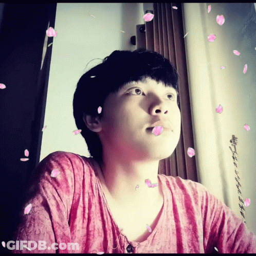 A Man In A Pink Shirt Is Surrounded By Petals GIF