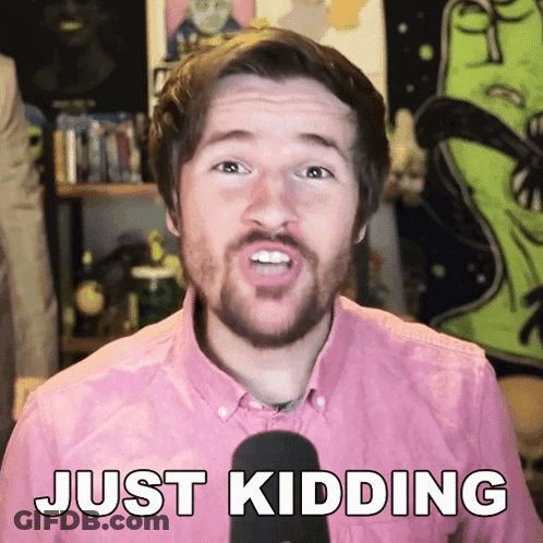 A Man In A Pink Shirt Is Talking Into A Microphone And Says Just Kidding GIF