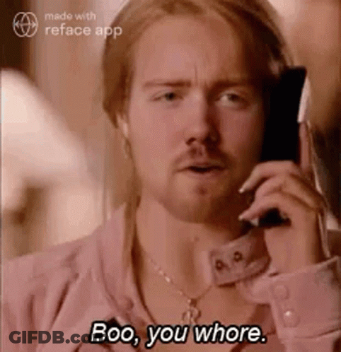A Man In A Pink Shirt Is Talking On A Cell Phone And Says Boo , You Whore . GIF