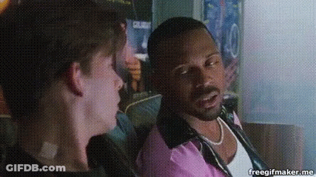 A Man In A Pink Shirt Is Talking To Another Man In A Black Shirt GIF