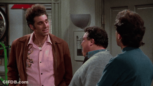 A Man In A Pink Shirt Is Talking To Two Other Men In A Room GIF