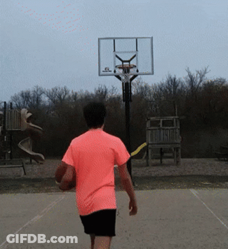 A Man In A Pink Shirt Is Walking Toward A Basketball Hoop GIF