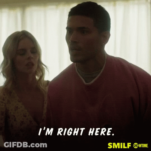 A Man In A Pink Shirt Says " I 'M Right Here " While Standing Next To A Woman GIF