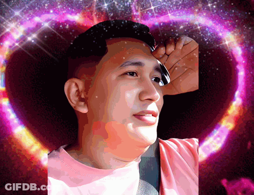 A Man In A Pink Shirt Stands In Front Of A Heart Shaped Background GIF