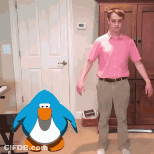A Man In A Pink Shirt Stands In Front Of A Penguin GIF