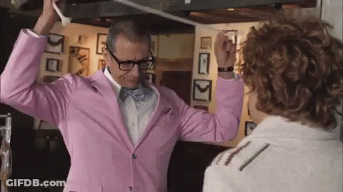 A Man In A Pink Suit And Bow Tie Is Dancing With Another Man . GIF