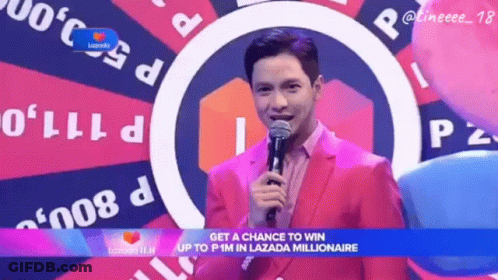 A Man In A Pink Suit Holds A Microphone In Front Of A Lazada Logo GIF